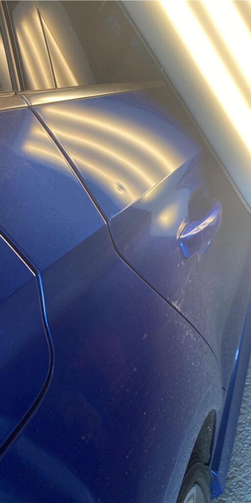 Delle in blauer Autotür vor der Reparatur