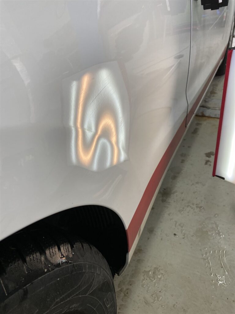 Delle in Autotür unter dem Fixierlicht, vor der Reparatur